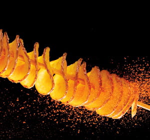 la pomme de terre est découpée en spirale avant d'être frite dans l'huile.